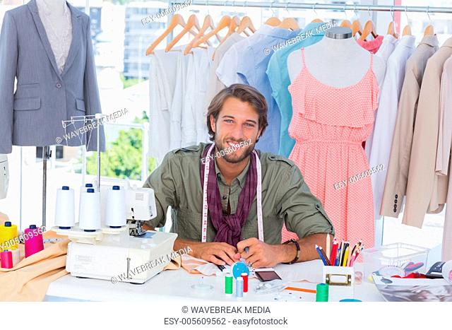 Smiling fashion designer sitting behind a desk