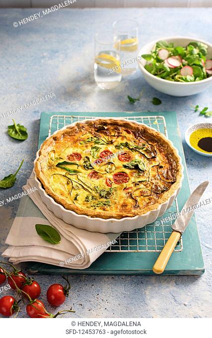 Spring quiche with cheese, spinach, tomatoes, courgette and spring onion