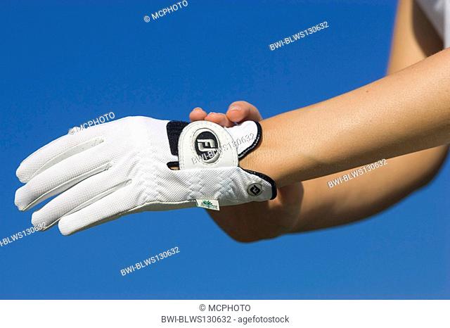 female golfer putting on her golf glove