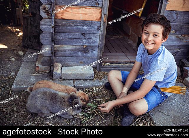 Smiling boy feeding rabbit in back yard