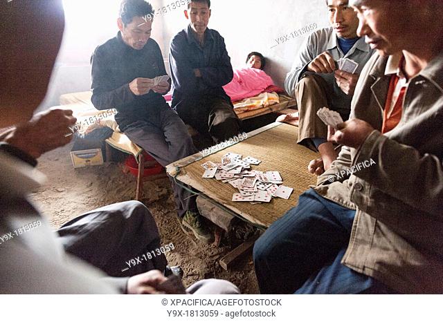 Labor workers playing a friendly game of cards at the San Huang Zhai Monastery on Song Mountain, China