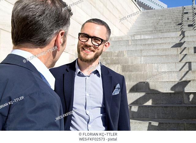 Two businessmen talking at stairs outdoors