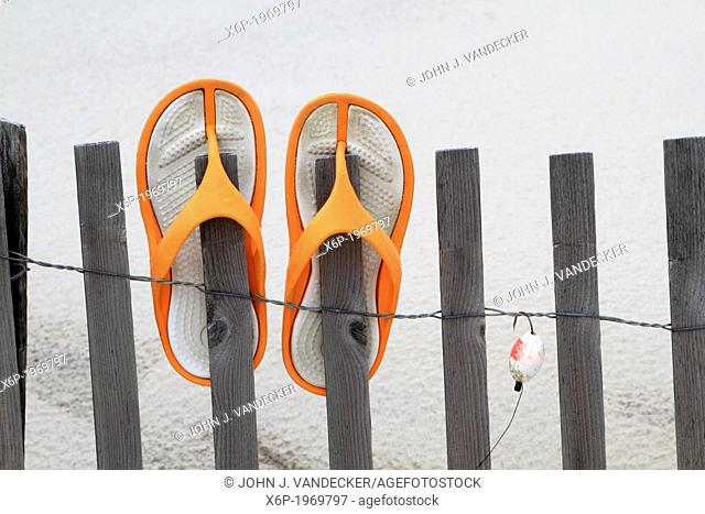 Flip Flops and fishing lure hanging on a beach dune fence. Lavalette, New Jersey, USA