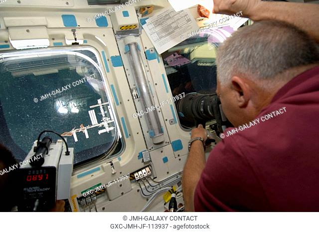 Onboard Endeavour's aft flight deck, astronaut Dave Wolf, STS-127 mission specialist, aims a camera at the International Space Station during rendezvous and...