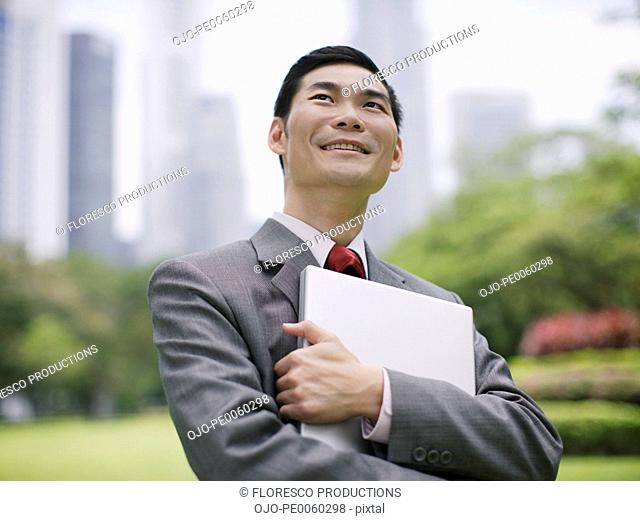 Businessman outdoors in park holding laptop