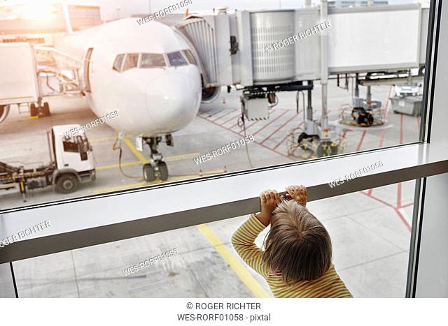 Little girl looking through window to airplane on the apron