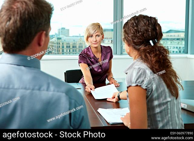 Attractive woman applicantshowing documents during job interview. Over the shoulder view