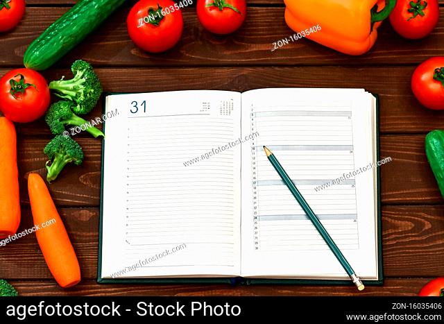 Diet regimen, vegetable image and diet menu plan on Notepad. The guy is recording a dietary program. new cooking recipes