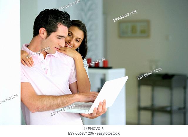 Couple stood at home with a laptop computer