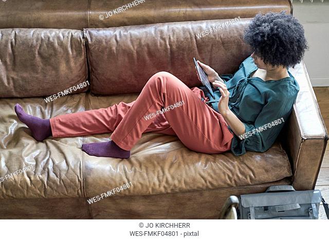 Young woman lying on couch using tablet