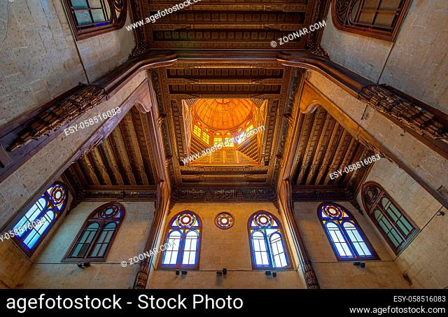 Wooden decorated dome mediating ornate ceiling with floral pattern decorations and stained glass windows at Sultan al Ghuri Mausoleum, Cairo, Egypt
