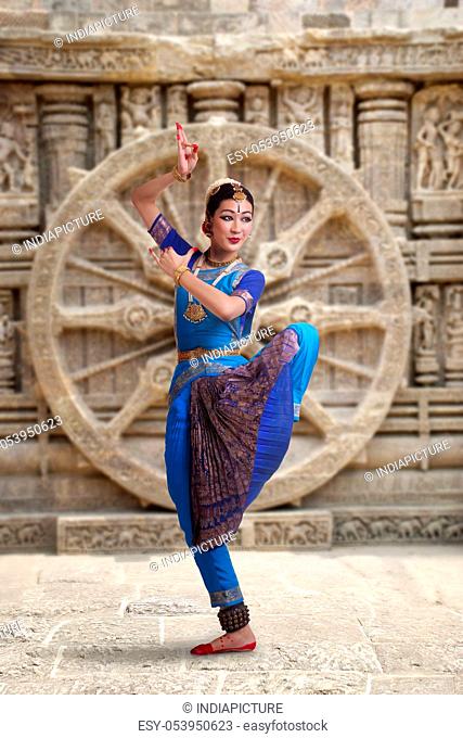 Full length of Bharatanatyam dancer performing against carved wall