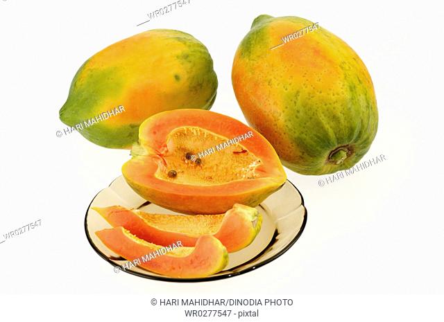 Fruits , two full Papaya with three small pieces kept in plate on white background