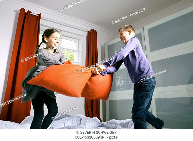 Children having pillow fight on bed