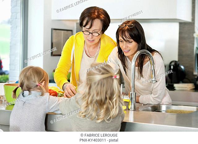 Two girls with her mother and grandmother working in a kitchen
