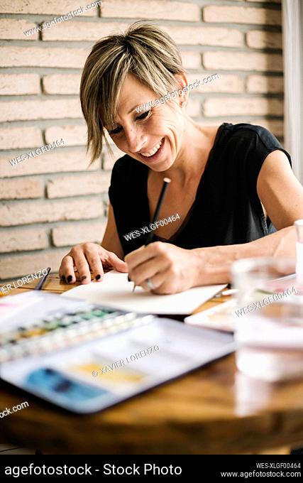 Smiling woman holding drawing on paper at home