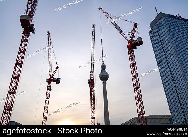 Berlin, Germany, Europe - The Berlin Television Tower at Alexanderplatz in Mitte district at dusk with construction cranes at the building site of the Covivio...
