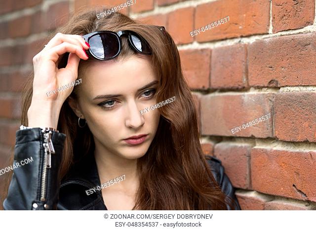 European girl with long hair near an old brick wall