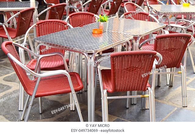 Open empty street cafe, tables and chairs with metal frame and wicker furniture, selective focus and close-up