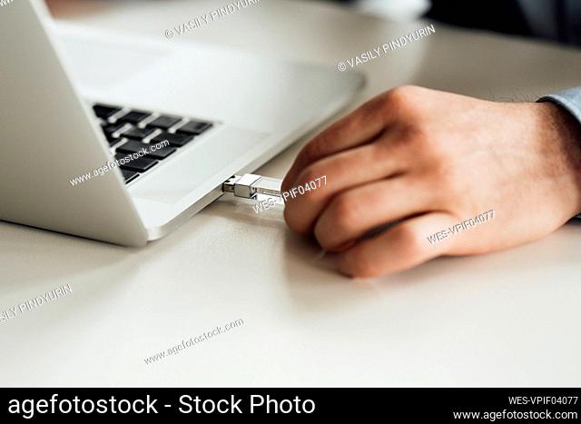 Businessman putting pen drive in laptop on desk