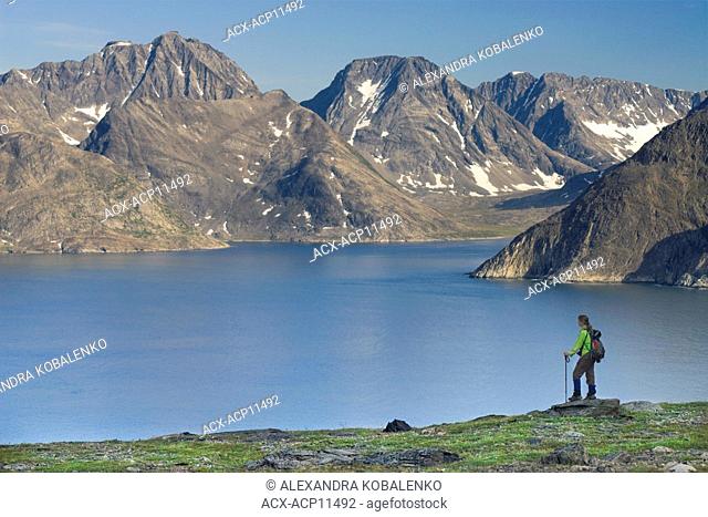 Hiker taking in the view of Ramah Bay and the Torngat Mountains, Labrador, Newfoundland and Labrador, Canada