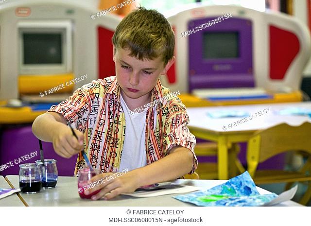 Young boy painting in a school