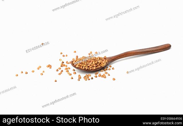 raw buckwheat grains in wooden spoon isolated on white background, top view