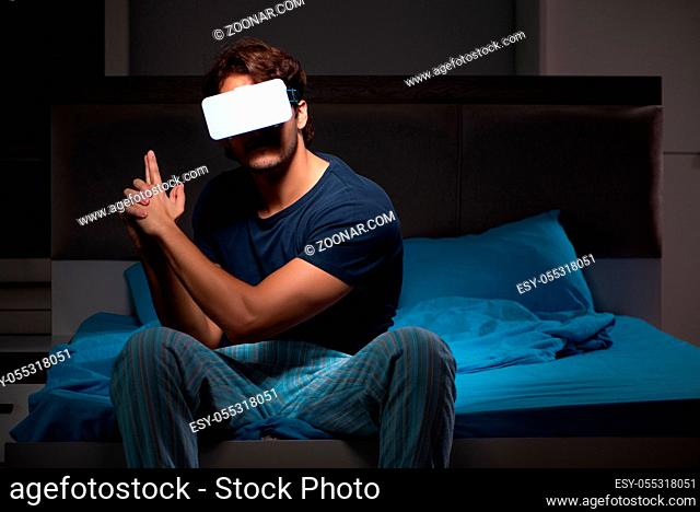 Young man playing computer games at night in bed