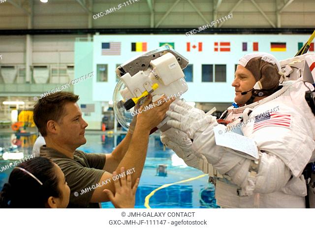 Astronaut Scott E. Parazynski, STS-120 mission specialist, dons a training version of the Extravehicular Mobility Unit (EMU) spacesuit prior to being submerged...