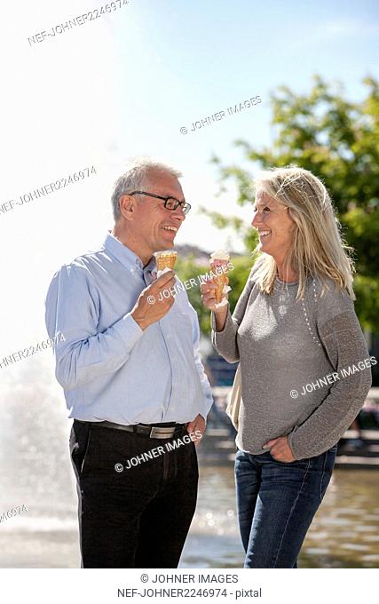 Mature couple eating ice creams in park