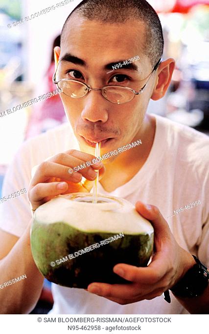 Man drinking coconut milk. Jatujak market. Bangkok, Thailand
