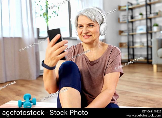 woman with phone and headphones exercising at home