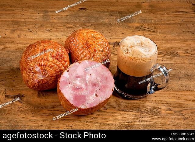 Ham sausage and mug of dark beer on a wooden desk