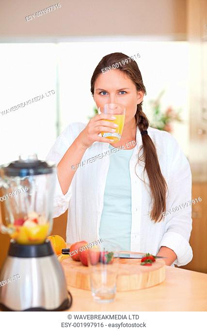 Portrait of a cute woman drinking fresh fruits juice in her kitchen