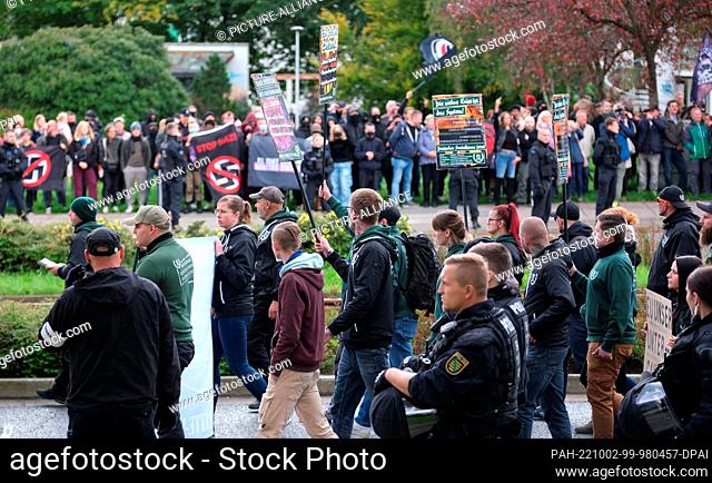 02 October 2022, Saxony, Plauen: Participants of a right-wing demonstration (in front) walk along a street, while in the background left-wing activists protest...