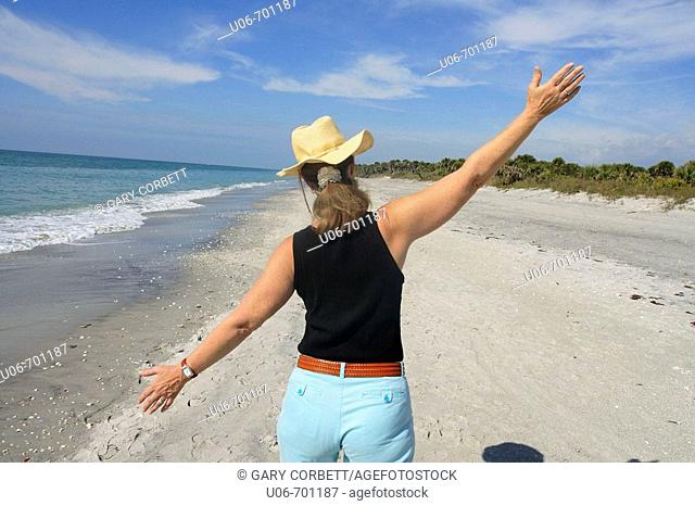 Senior woman walking at Casperson Beach in Venice (Florida, USA) with arms wide open