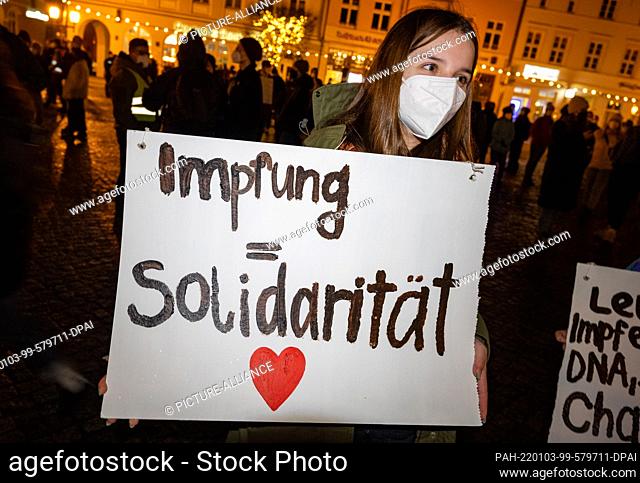 03 January 2022, Mecklenburg-Western Pomerania, Greifswald: A demonstrator shows a poster with the writing ""Vaccination = Solidarity""