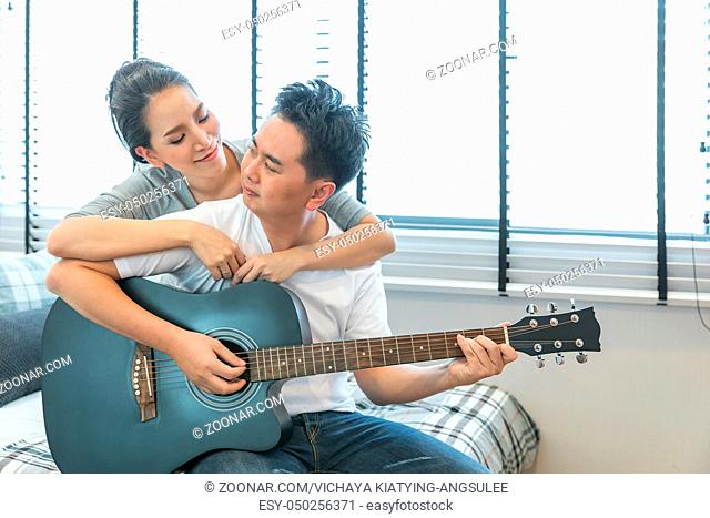 Young Couples playing guitar tohether in bedroom of contemporary house for modern lifestyle concept