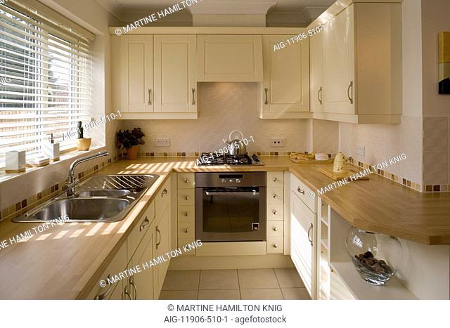 Modern galley kitchen in traditional style with timber worktops and cream paintwork