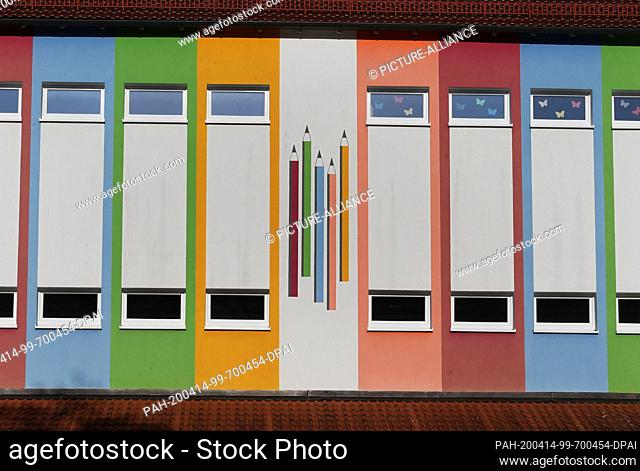 14 April 2020, Bavaria, Bad Wörishofen: Coloured pencils are painted on the colourful facade of the parish Kneipp primary and secondary school
