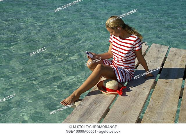 woman is sitting on a footbridge and listen to the musik