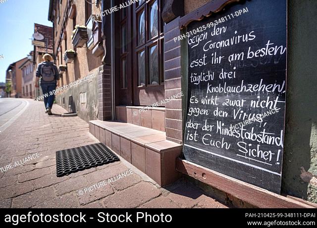 25 April 2021, Hessen, Fränkisch-Crumbach: At a closed inn hangs a sign with the inscription ""Against the Coronavirus you eat best daily three garlic cloves