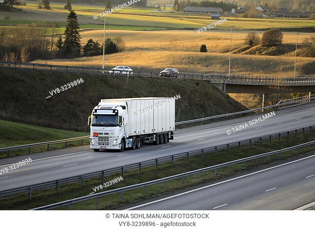 Salo, Finland - November 18, 2018: White Volvo FH semi trailer driving among motorway traffic at sunset time in late autumn