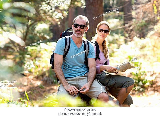 Hiker couple sitting on rock with map