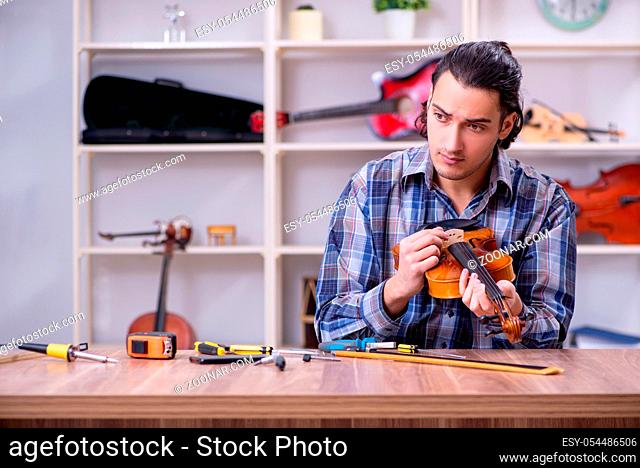 The young handsome repairman repairing violin