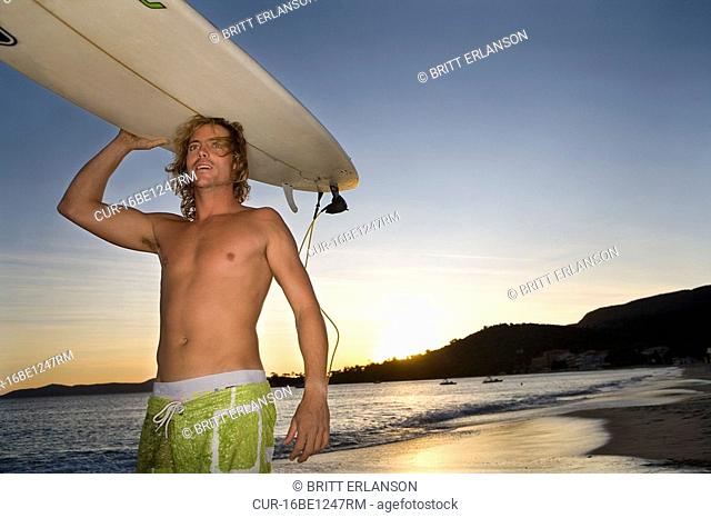 man with surfboard on head