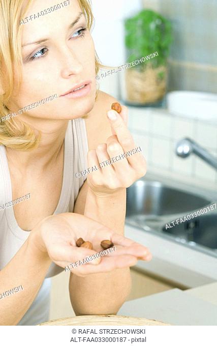Woman eating nuts, looking away