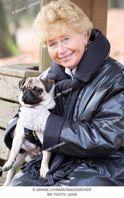 Senior holding her young pug on her lap