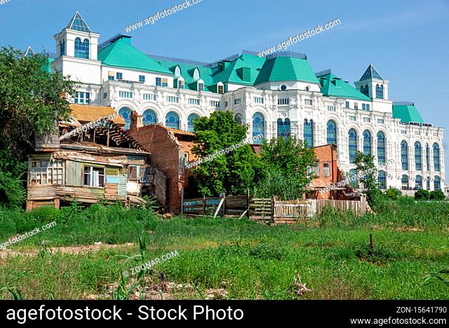 Astrakhan/Russia-20.06.2016:The contrast of russian reality: old abandoned house and new and modern theatre in Astrakhan
