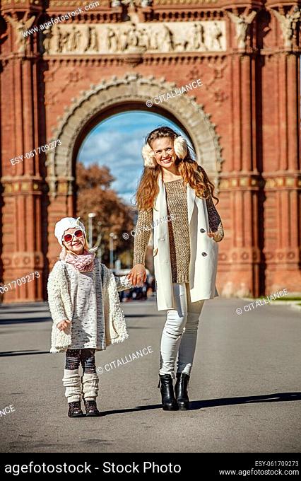 in Barcelona for a perfect winter. Full length portrait of happy trendy mother and child standing near Arc de Triomf in Barcelona, Spain